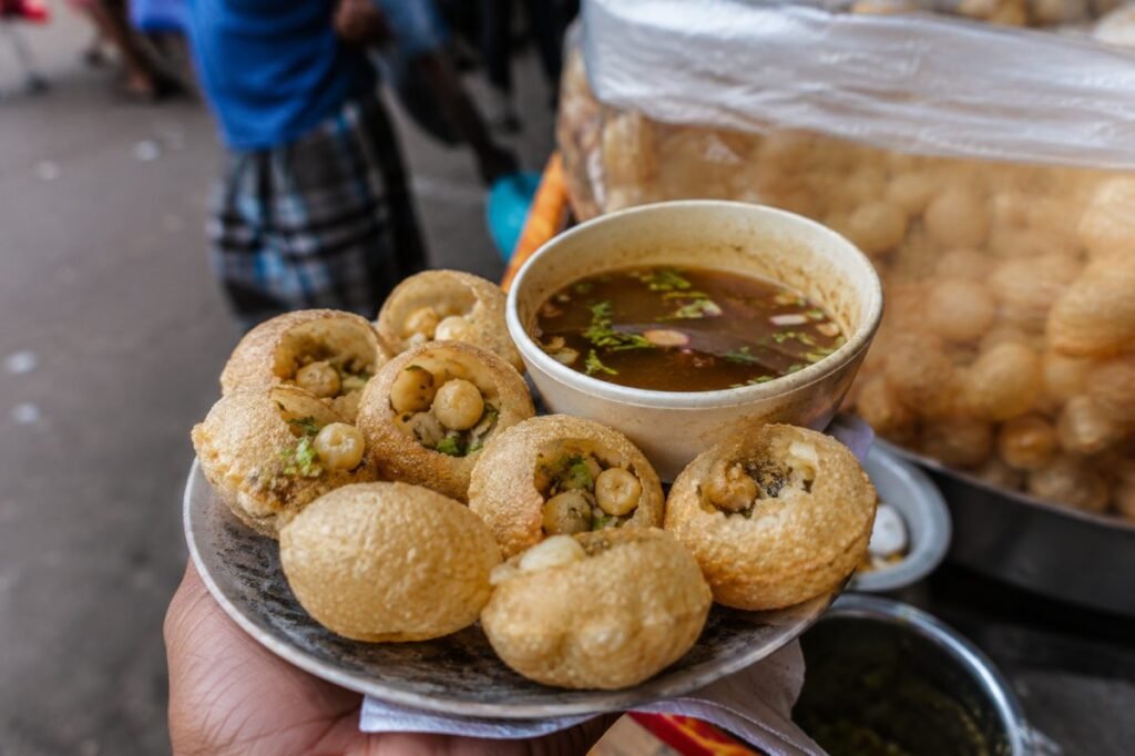 Fuchka, crisp shells stuffed with spiced chickpeas, egg and tamarind water, Bangladesh street food, anime style